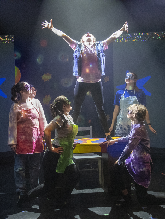 Theatre production with single person surrounded by five actors